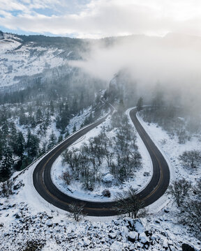 Horseshoe bend at Rowena Crest as Highway 30 road curves and twists around high bluffs along on the south side of the Columbia River Gorge, Mosier, Oregon. This winter scence features snow and fog.