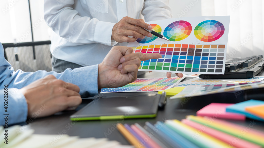 Poster graphic designer or creative working together coloring using graphics tablet and a stylus at desk wi