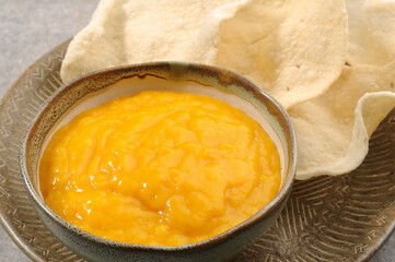 thick alphanso mango juice or pulp served with rice papad or chips in India 