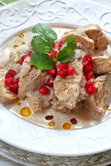 Chicken satsivi on white wooden background with pomegranate seeds