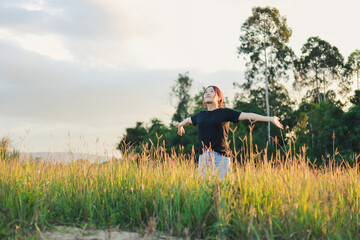 Obraz premium woman wearing a black T-shirt and jeans, rejoices in the green fields