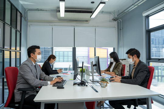 Group of Asian business people wearing protective mask to Protect Against Covid-19 working and communicating together in office.