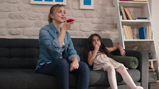 Little girl and her mother talking on the open phone in megaphone.Mother and daughter talking on the phone, holding the microphone on.