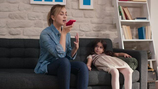 Little girl and her mother talking on the open phone in megaphone.Mother and daughter talking on the phone, holding the microphone on.
