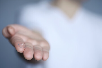 The concept of poor vision. Hold a contact lens and glasses in hand. A poster for advertising...