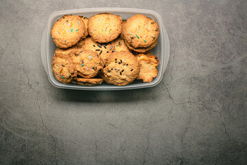 Homemade crunchy chocolate cookies chips on a plastic container on a grey background