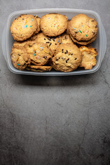 Homemade crunchy chocolate cookies chips on a plastic container on a grey background