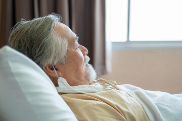Senior patient rests lying on the bed at hospital.