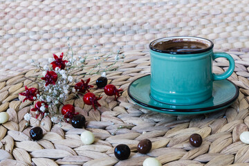 Fototapeta na wymiar Turkish coffee and flowers on wicker american service. Turkish coffee and flowers in the green cup. Coffee tradition belonging to Turkish culture.