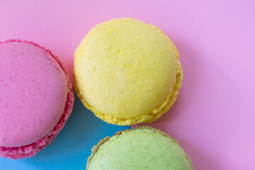 Traditional french dessert macaroons yellow, green and pink on two colored background. Close up photo of pastry bisquits