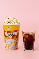 Popcorn and soda with ice cubes on black background