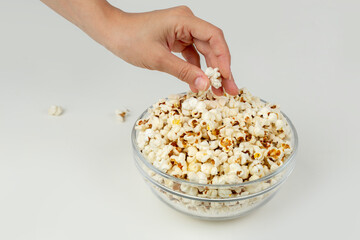 Popcorn in a bowl and woman's hand taking one