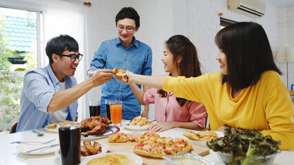 Happy young friends group having lunch at home. Asia family party eating pizza food and laughing...