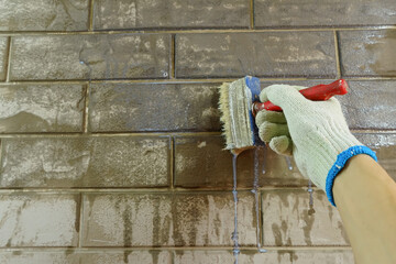 A construction worker applies paint to a brick wall.The painter paints primers the walls with a...