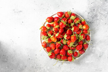 Strawberry. Strawberries in a white ceramic plate on a light gray background. Lots of strawberries. Top view with copyspace