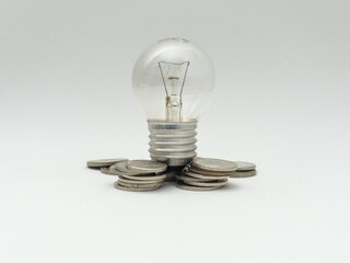 Isolated Bulb with coins. Money spent with light bulbs. Concept of energy efficiency