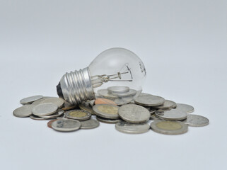 Isolated Bulb with coins. Money spent with light bulbs. Concept of energy efficiency