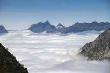a sea of clouds runs through a glacial valley surrounded by high mountains