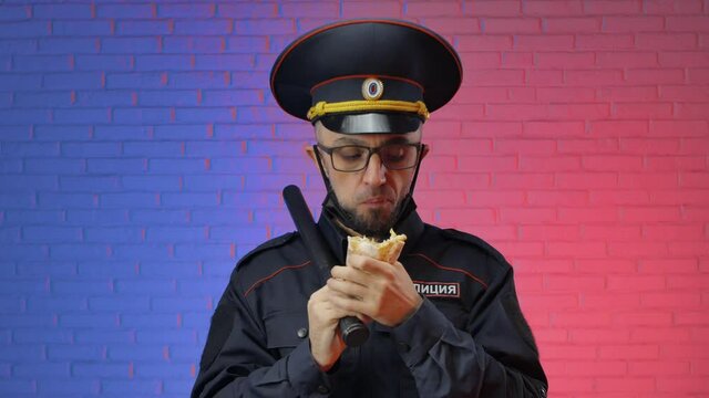 funny man in a military uniform of the Russian police with a coronavirus mask eats fast food shaverma. English translation police, Russia