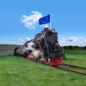An old vintage steam train with an EU flag waving on the roof