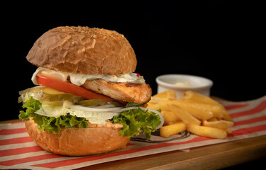 fresh made burger with cheese and vegetables on the dark background