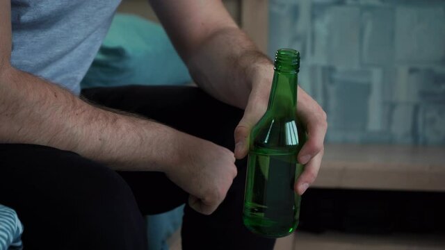 man's hands holding a bottle of beer