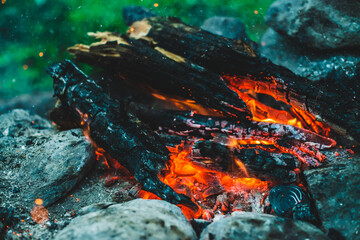 Vivid smoldered firewoods burned in fire closeup. Atmospheric background with orange flame of...