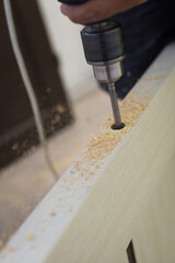 Drilling a hole in the furniture to install a lock on the door close-up.