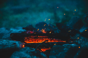 Vivid smoldered firewoods burned in fire close-up. Atmospheric warm background with orange flame of...