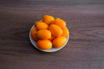 little oranges kumquats in a bowl on a wooden table
