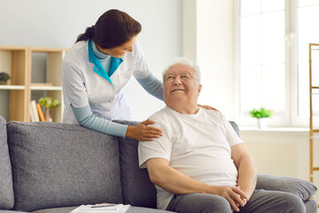 Obraz premium Friendly female doctor visits, supports and encourages her senior patient at home.