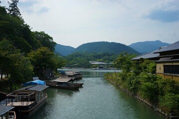 Fototapeta na wymiar Landscape of Katsuragawa River with tour boat from Togetsu Bridge in Arashiyama, Kyoto, Japan - 京都 嵐山 桂川
