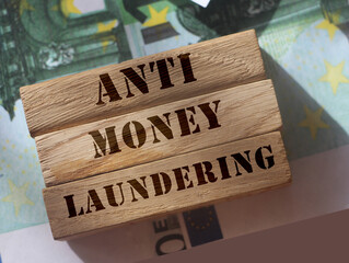 Anti Money laundering concept, words on wooden blocks on 100 euro banknotes