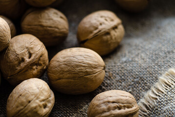 Walnuts lie in heap on gray background of coarse burlap