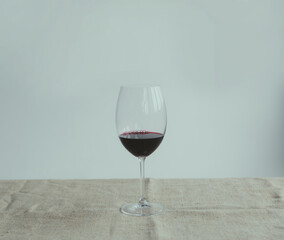 A glass of red wine on a white background on a beige fabric.