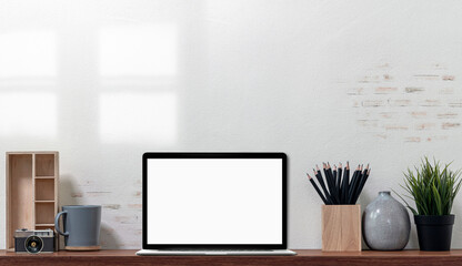 Mockup blank screen laptop computer on wooden table in loft modern office room.