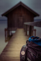 Fototapeta premium Bootshaus am See, Rucksack mit Aufschrift Abenteuer