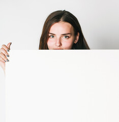 Fototapeta premium young pretty brunette girl with placard shit copyspace on white background wearing business costume student