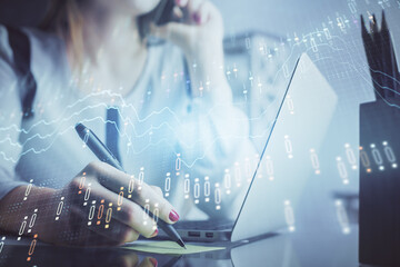 Double exposure of woman hands typing on computer and financial graph hologram drawing. Stock market analysis concept.