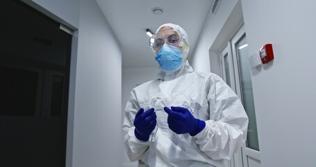Woman getting dressed in full protective PPE suit or clothing during the Covid-19 coronavirus...