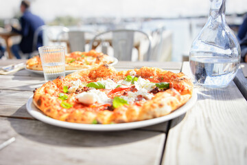 Close-up of a delicious pizza in a restaurant by the sea. Warm summer mood concept.