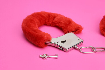 pink handcuffs with key, on pink background