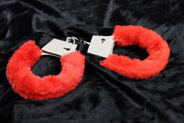 pink fluffy handcuffs on black velvet. Valentine's Day