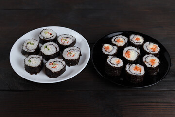Fresh delicious sushi rolls in plates on a wooden table
