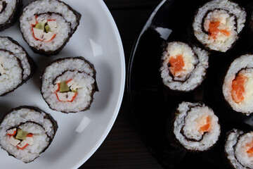 Fresh delicious sushi rolls set in plates on a wooden table