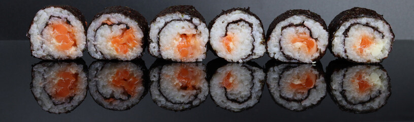 row of fresh delicious sushi rolls on a mirrored surface