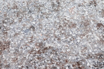 Cracked ice on concrete with yellow leaves. Yellow leaves and concrete can be seen under the cracked ice
