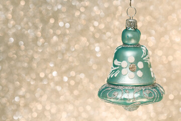 Christmas bauble in bell shape decorated with glitter on golden background