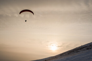 a man on a parachute descends against the backdrop of a beautiful sunset