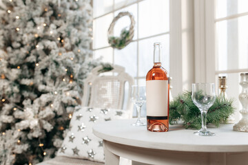 Christmas festive decoration with garlands, bottle wine, glasses, golden balls and fir tree.